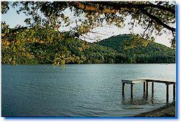 A dock overlooking clear water with green hills in the background.